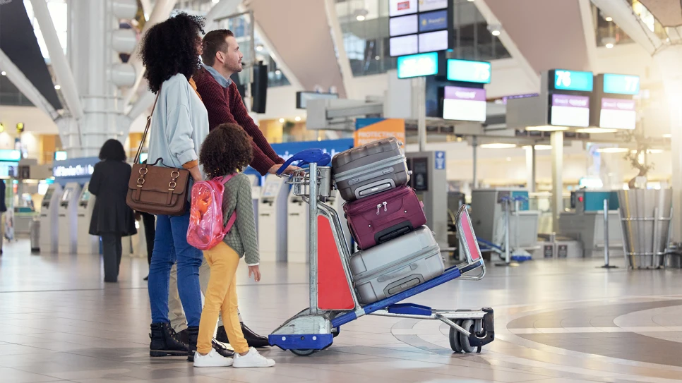 Family standing beside a luggage cart stacked with suitcases inside Incheon Airport