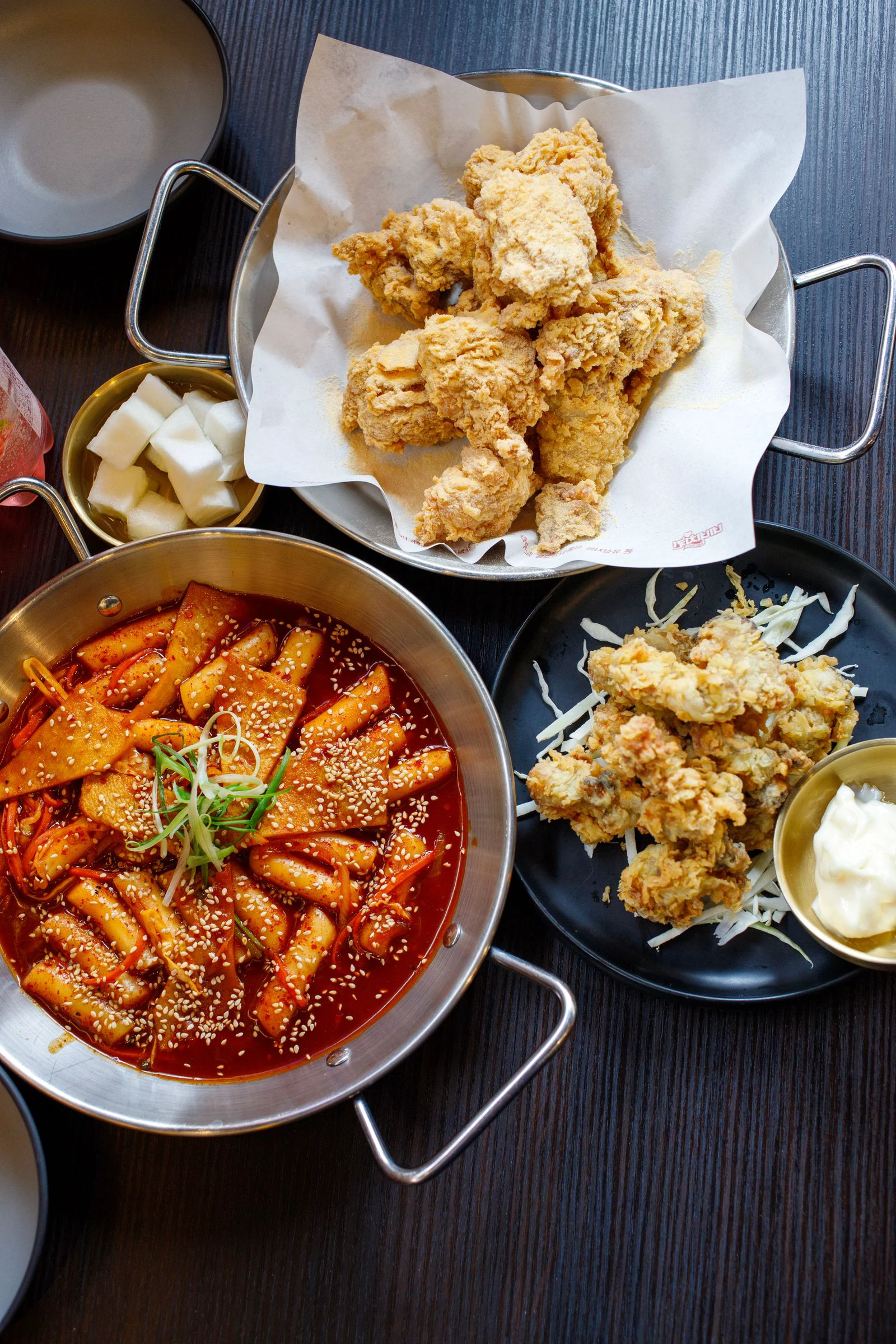 Korean fried chicken served with cubed pickled radish and a separate pan of tteokbokki