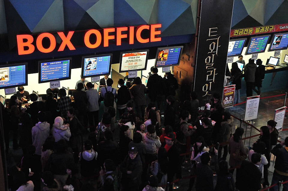 Penonton menunggu di bawah papan box office terang di bioskop Megabox Seoul