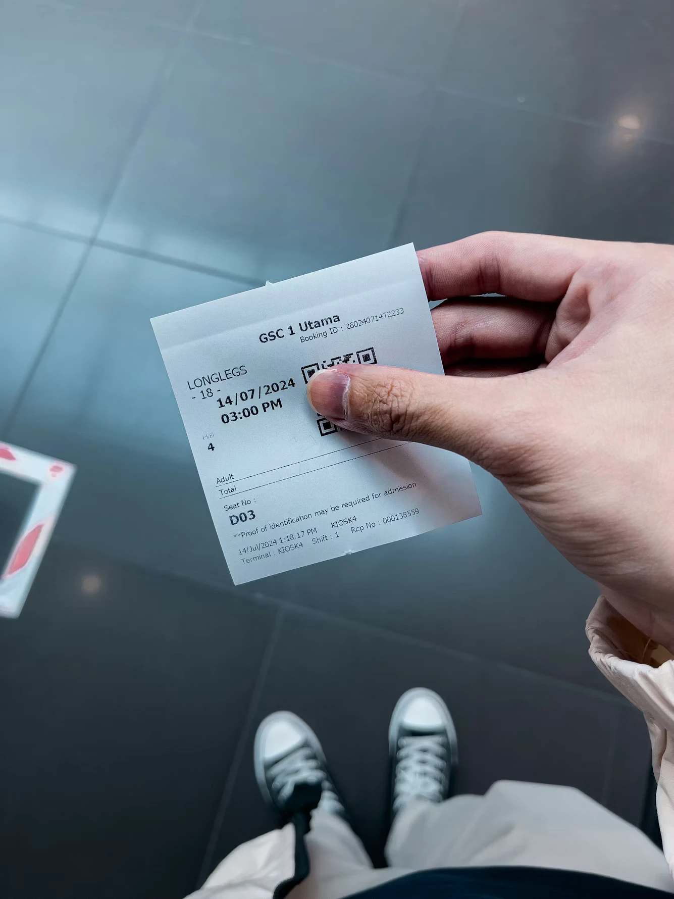 Penggemar memegang tiket acara cetak dengan sebagian kode QR tertutup