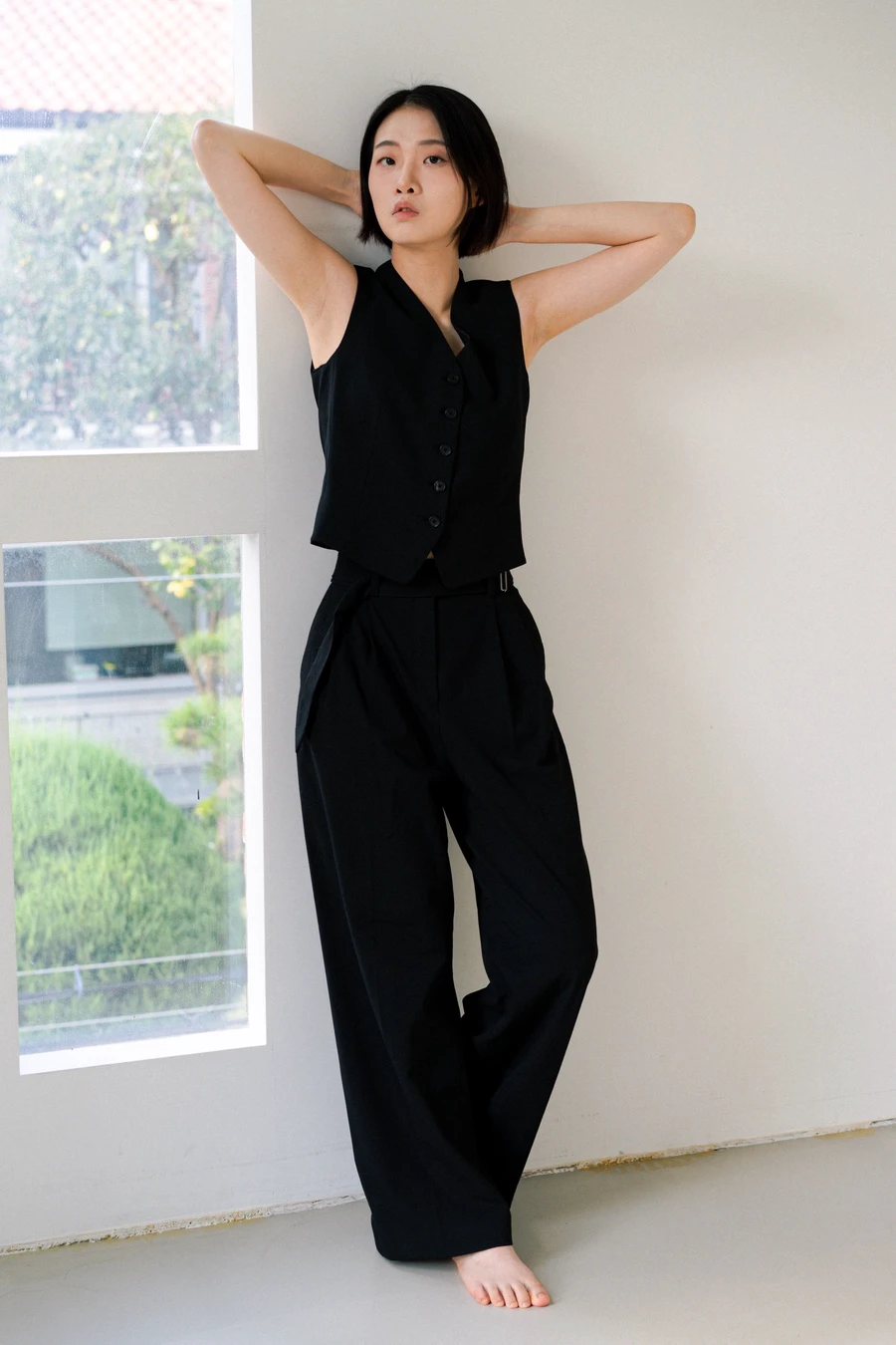 Full-length front view of a black buttoned vest with wide black trousers