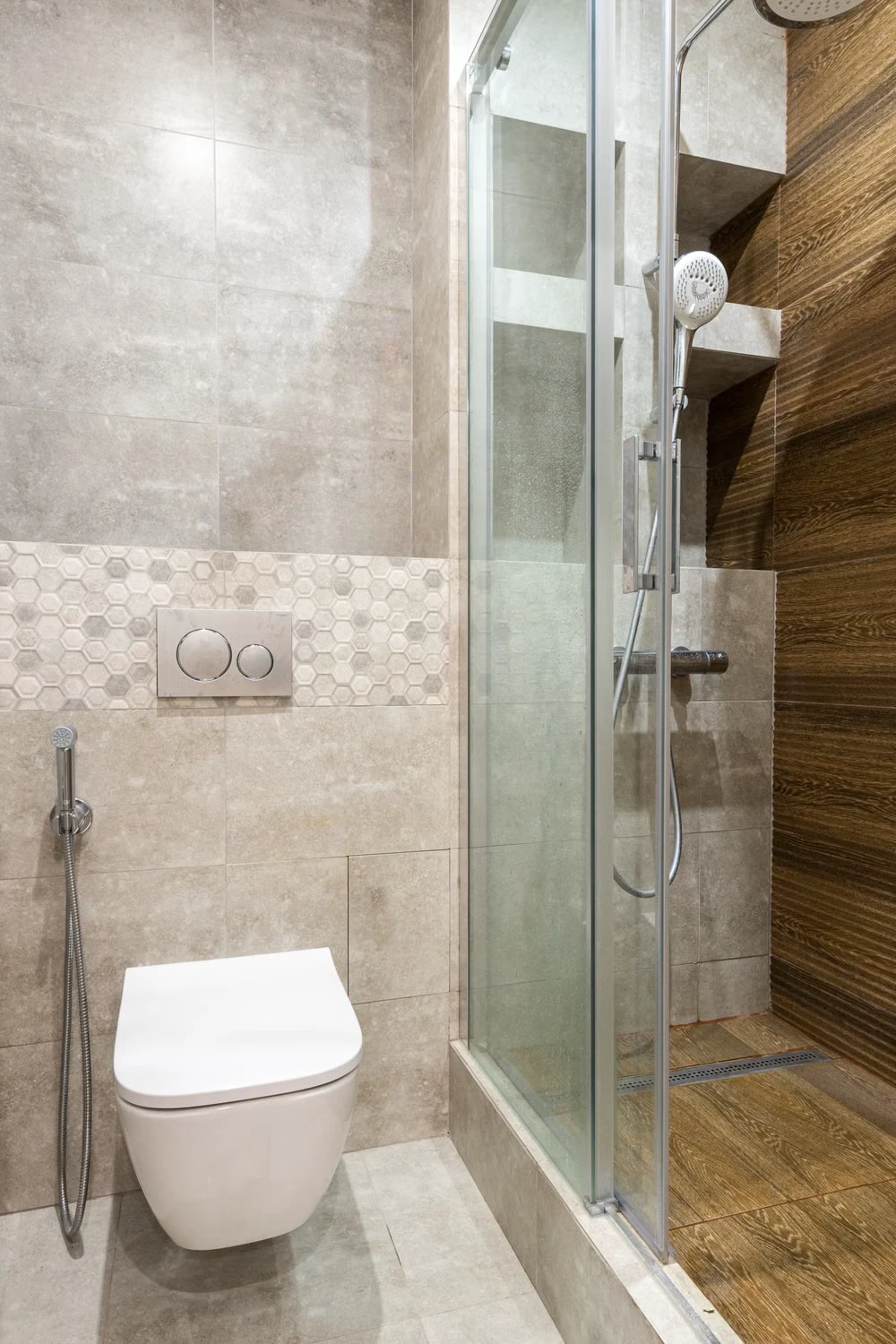 Compact tiled bathroom with a toilet beside a glass shower stall and no bathtub