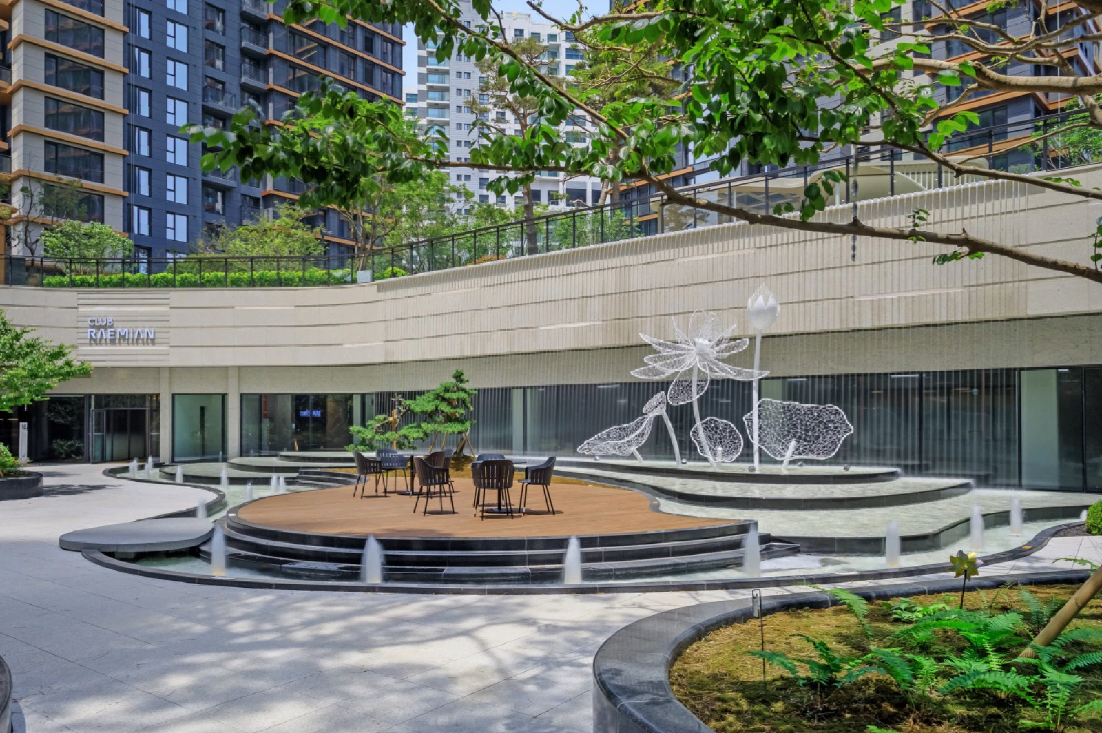 Sunken courtyard at Raemian One Pentas with a Club Raemian sign, seating and apartment towers