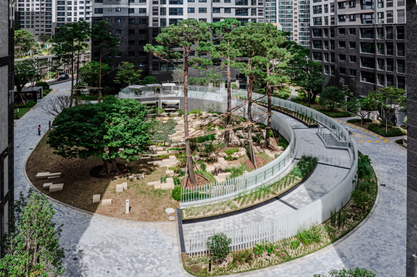 Landscaped garden and curved walkway between apartment towers at Raemian Forestige