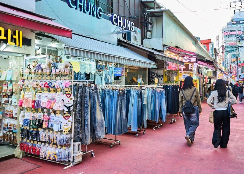 Shoppers walking past outdoor clothing racks along Hongdae R3 Fashion Street