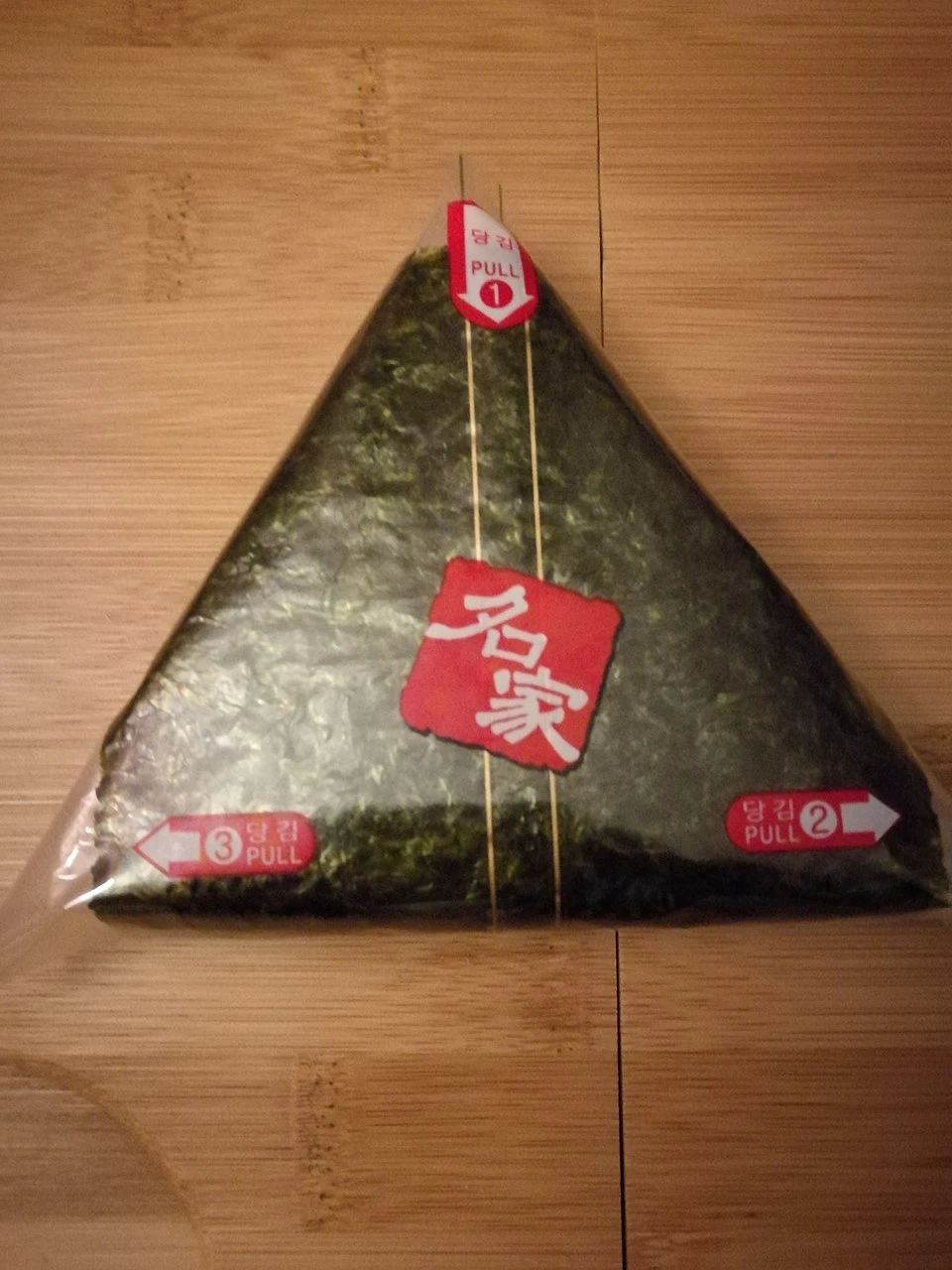 Packaged Korean triangle gimbap with numbered pull tabs one, two, and three