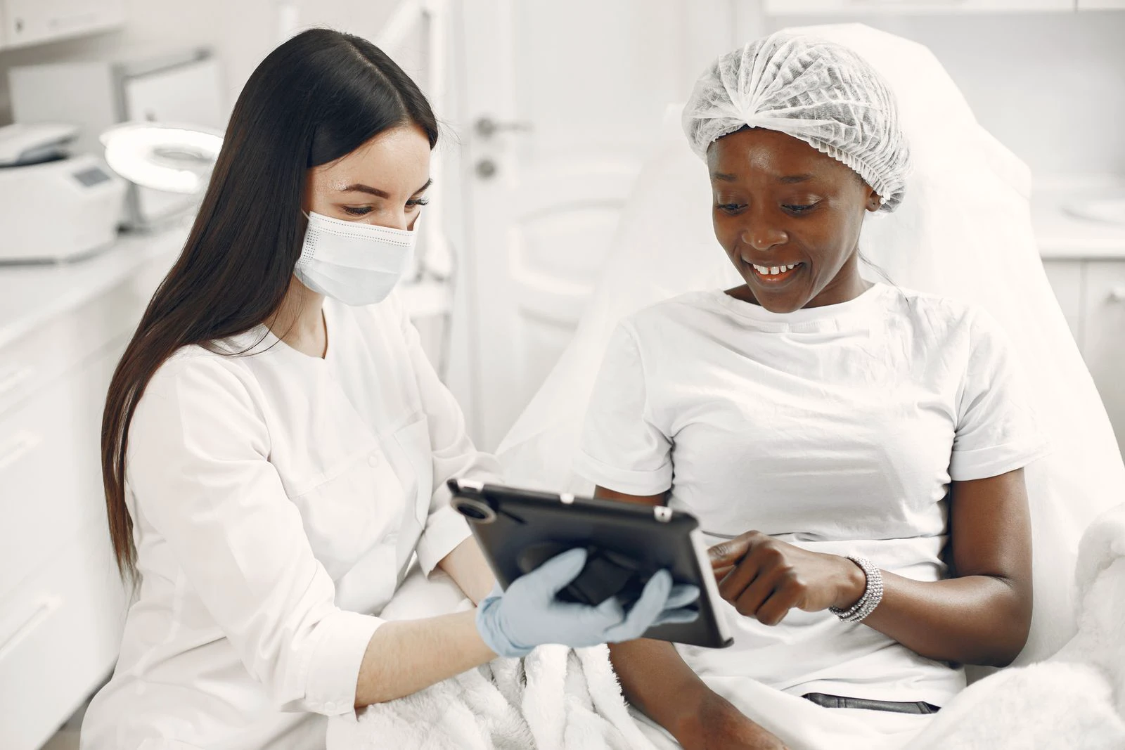 Skin-care practitioner and client reviewing information together on a tablet during a consultation