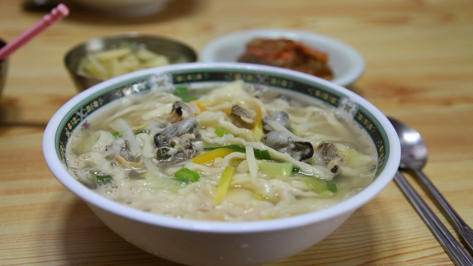 Bowl of hot bajirak kalguksu with thick knife-cut noodles, clams, and green onion