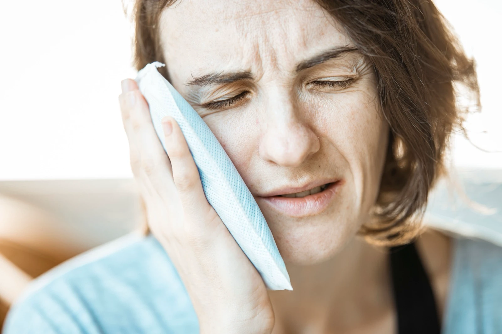 Woman holding a cold compress to her cheek to illustrate visible recovery time