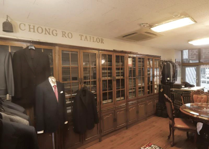 Interior of a long-established Seoul tailor shop with finished suits and wooden fabric cabinets