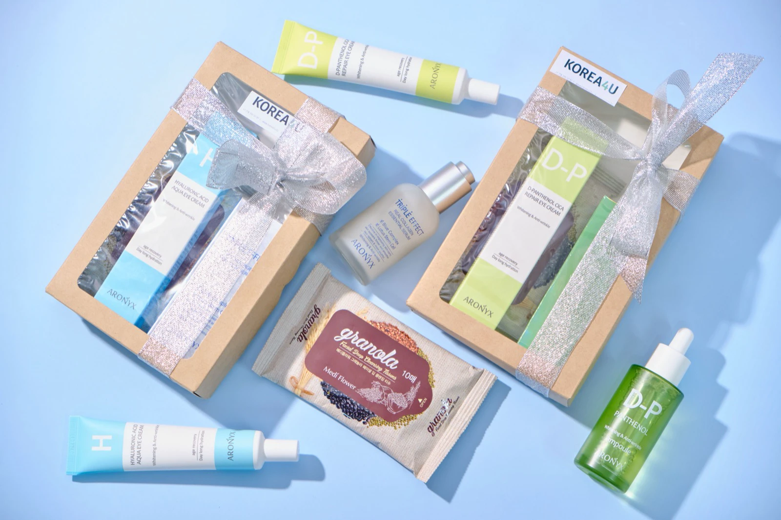 Dua kotak paket skincare Korea dengan serum dan krim di atas latar biru