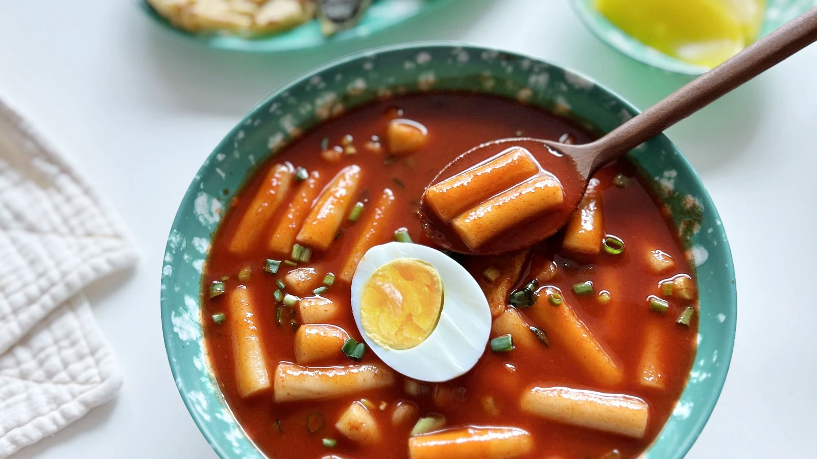 Slim wheat-based tteok in red tteokbokki sauce with boiled egg