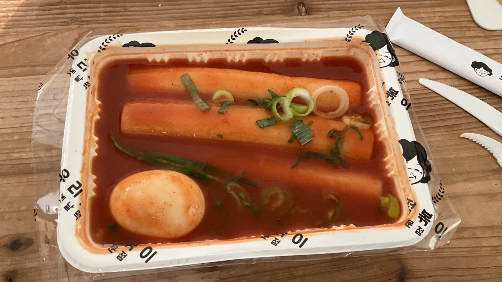 Thick garaetteok-style rice cakes in red tteokbokki sauce with a boiled egg