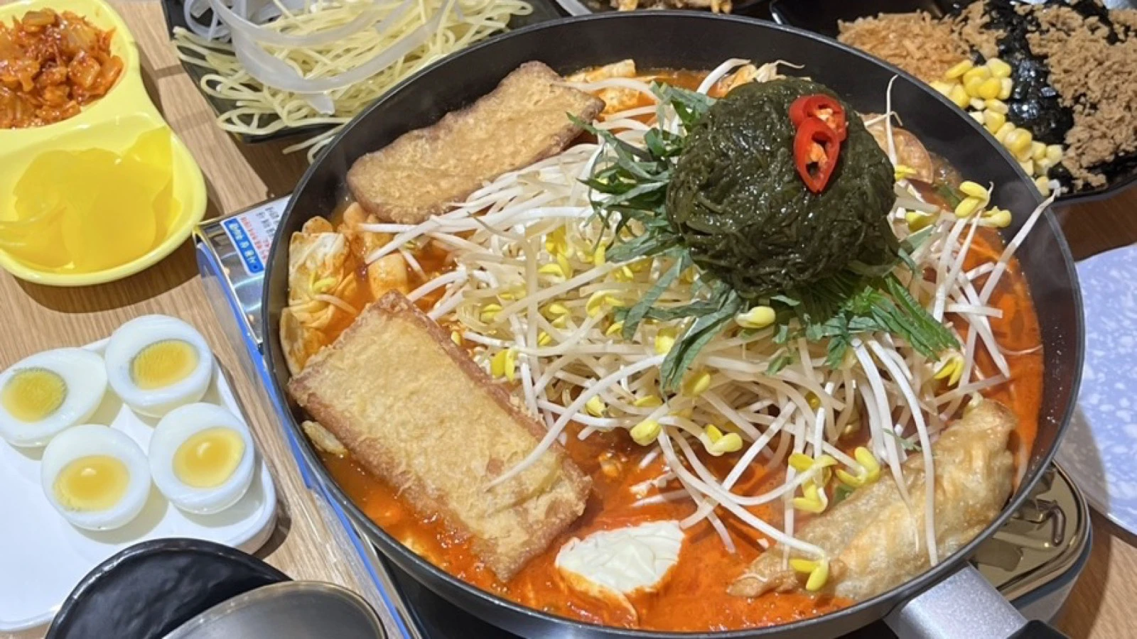 Jeukseok tteokbokki cooking in a wide tabletop pan with fish cake, bean sprouts and noodles