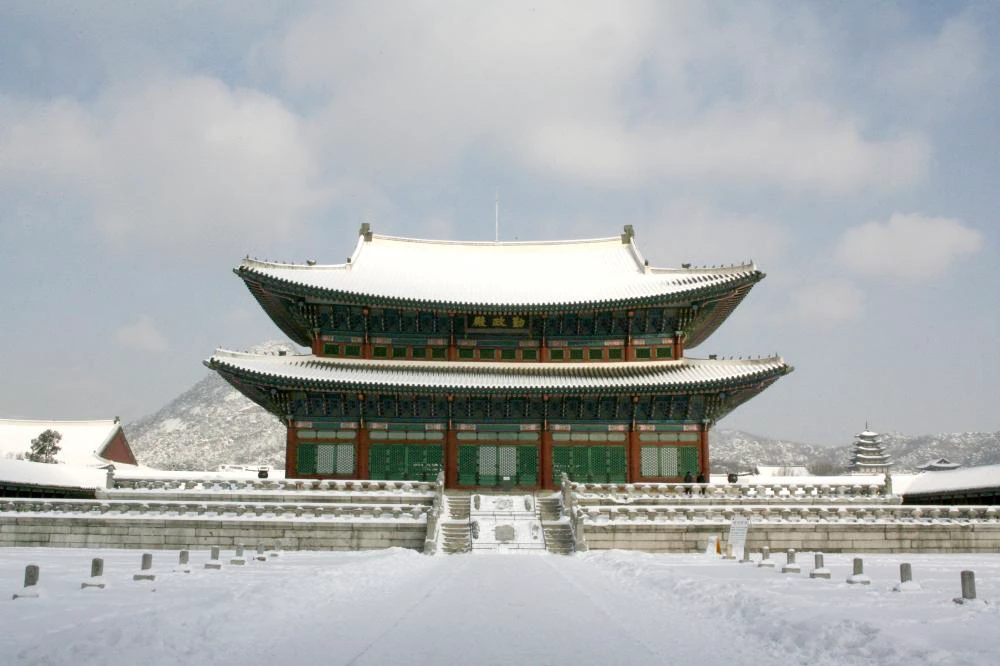 Geunjeongjeon Hall at Gyeongbokgung with snow covering the roof, steps, and open courtyard