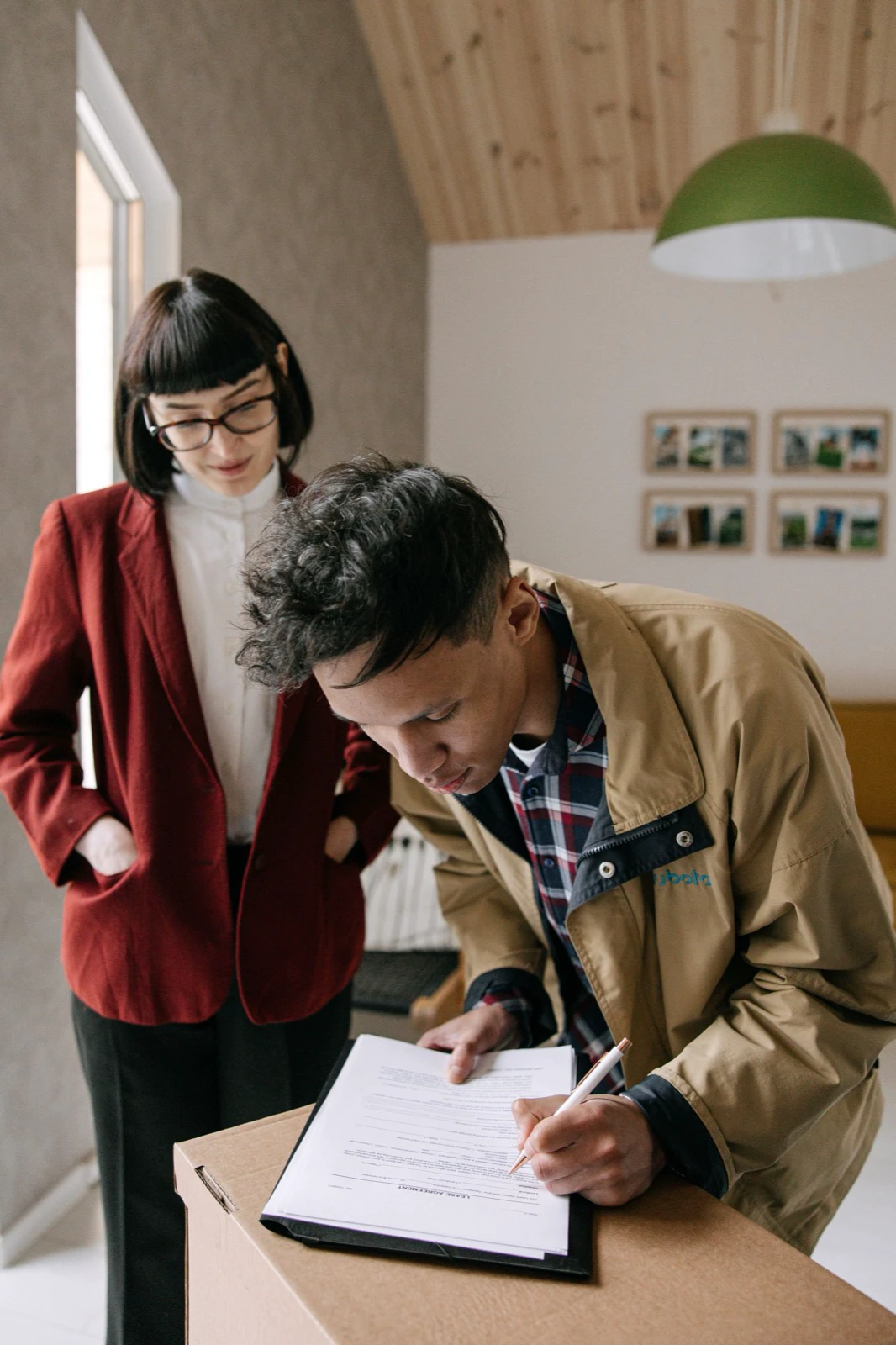 A prospective renter signing a document while a real-estate agent observes