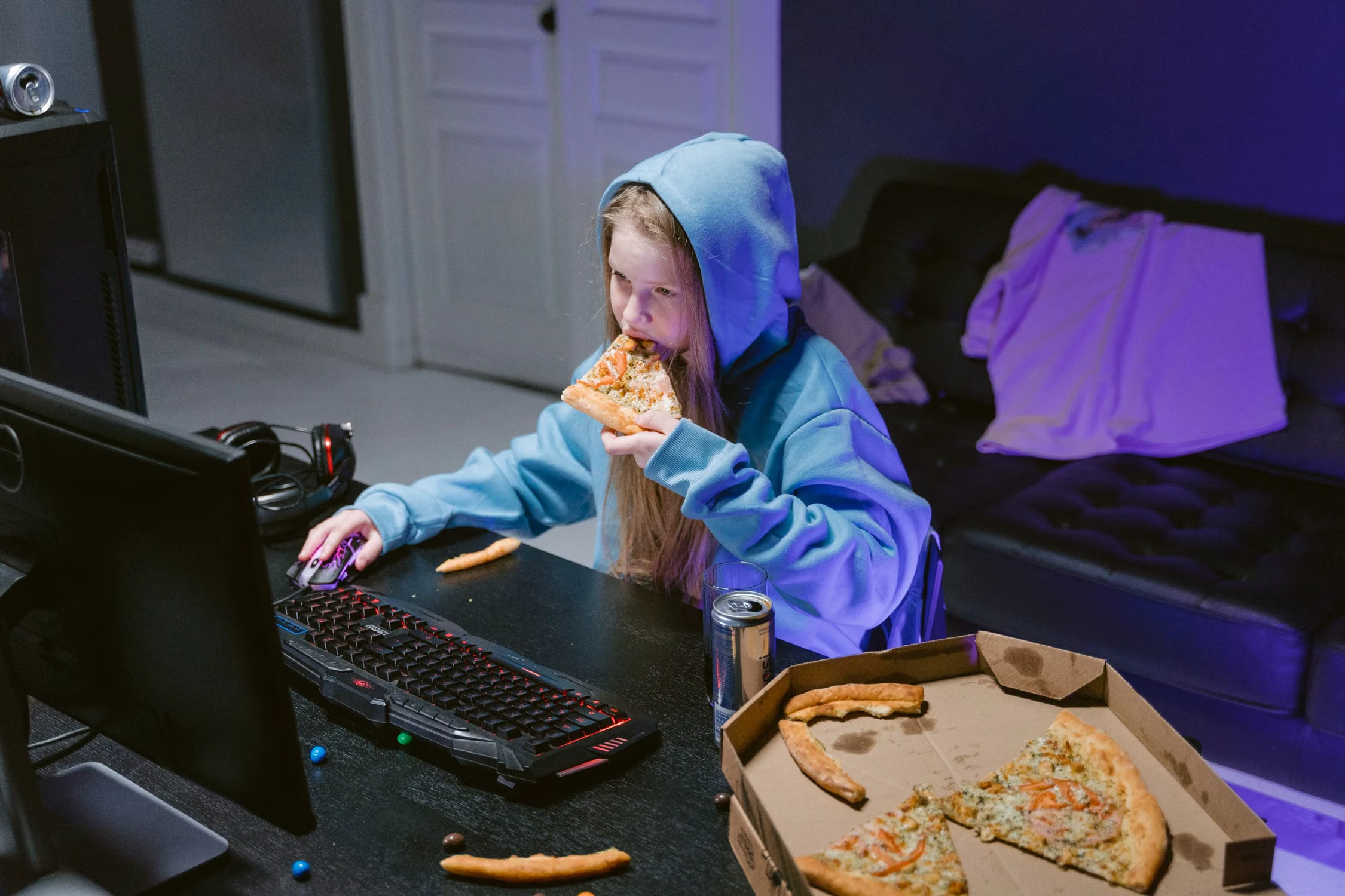 Gamer eating pizza while using a computer at a gaming desk