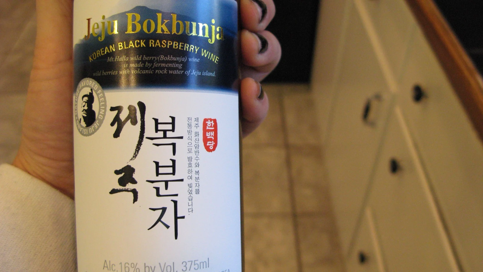 A bottle labeled Korean black raspberry bokbunja wine held close to the camera