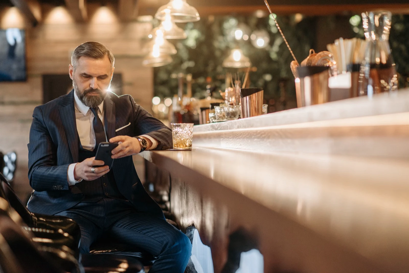 A solo customer sits with a drink at a long bar counter