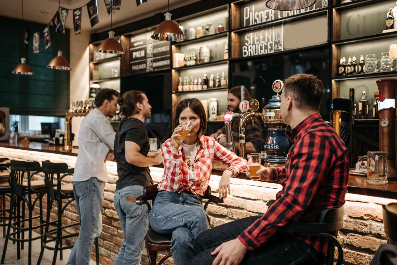 Several customers sit and stand together around a pub bar counter