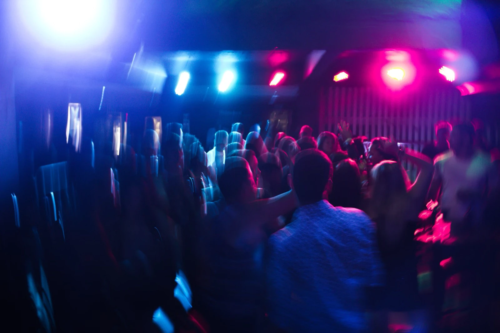 A blurred nightclub crowd under blue and magenta lights
