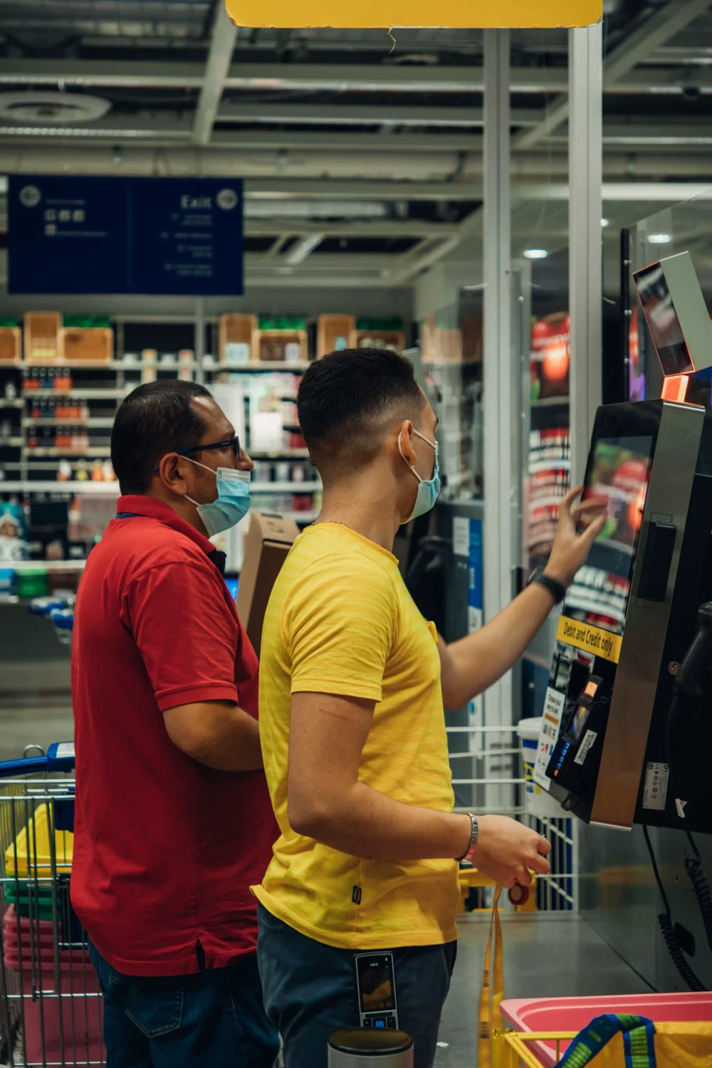 Two shoppers using a touchscreen self-checkout terminal