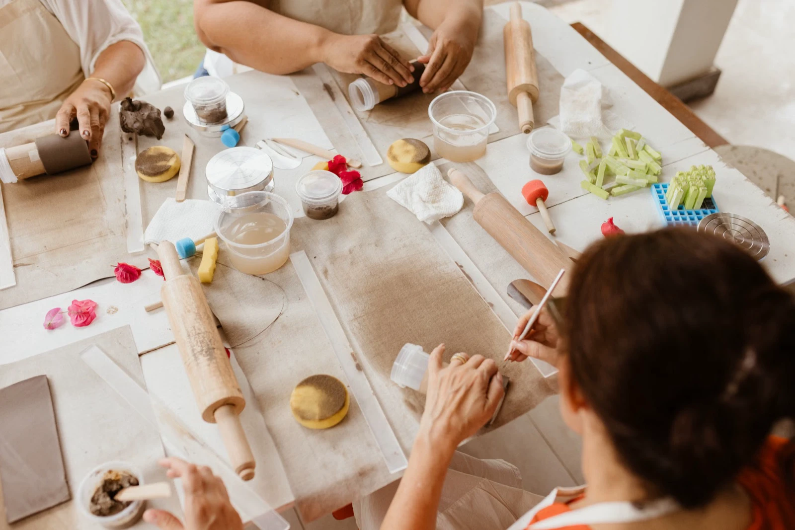 Adults working with clay and craft tools around a shared table