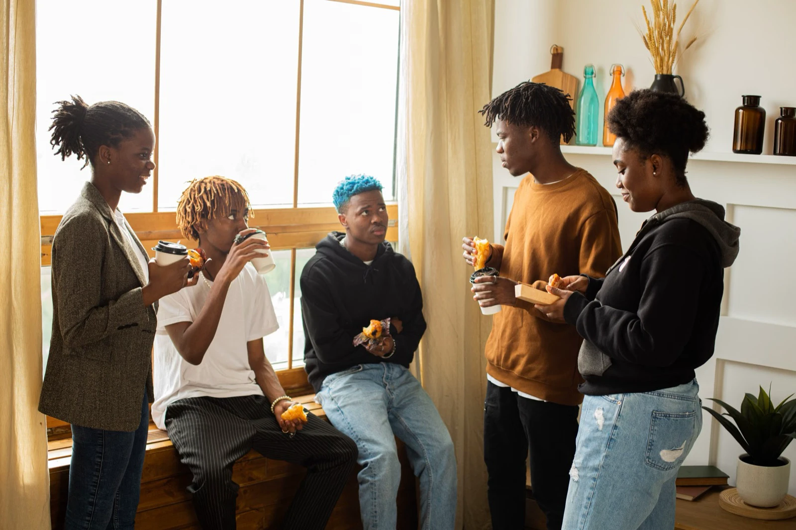 Five adults talking over snacks in a bright room