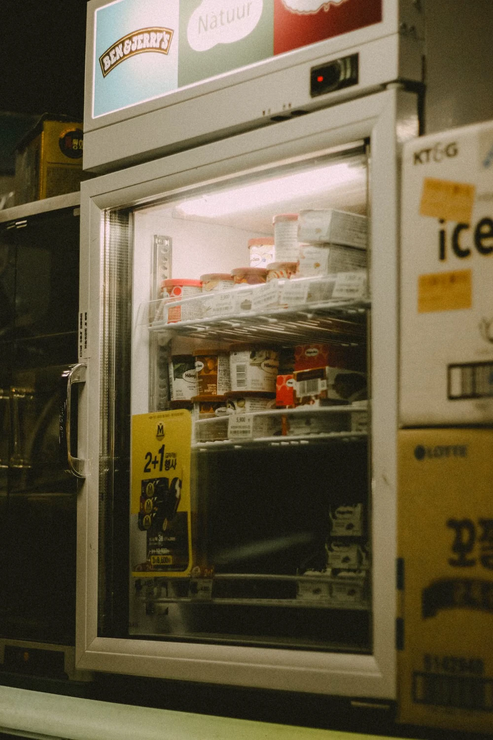 Glass-door store freezer stocked with packaged ice cream tubs