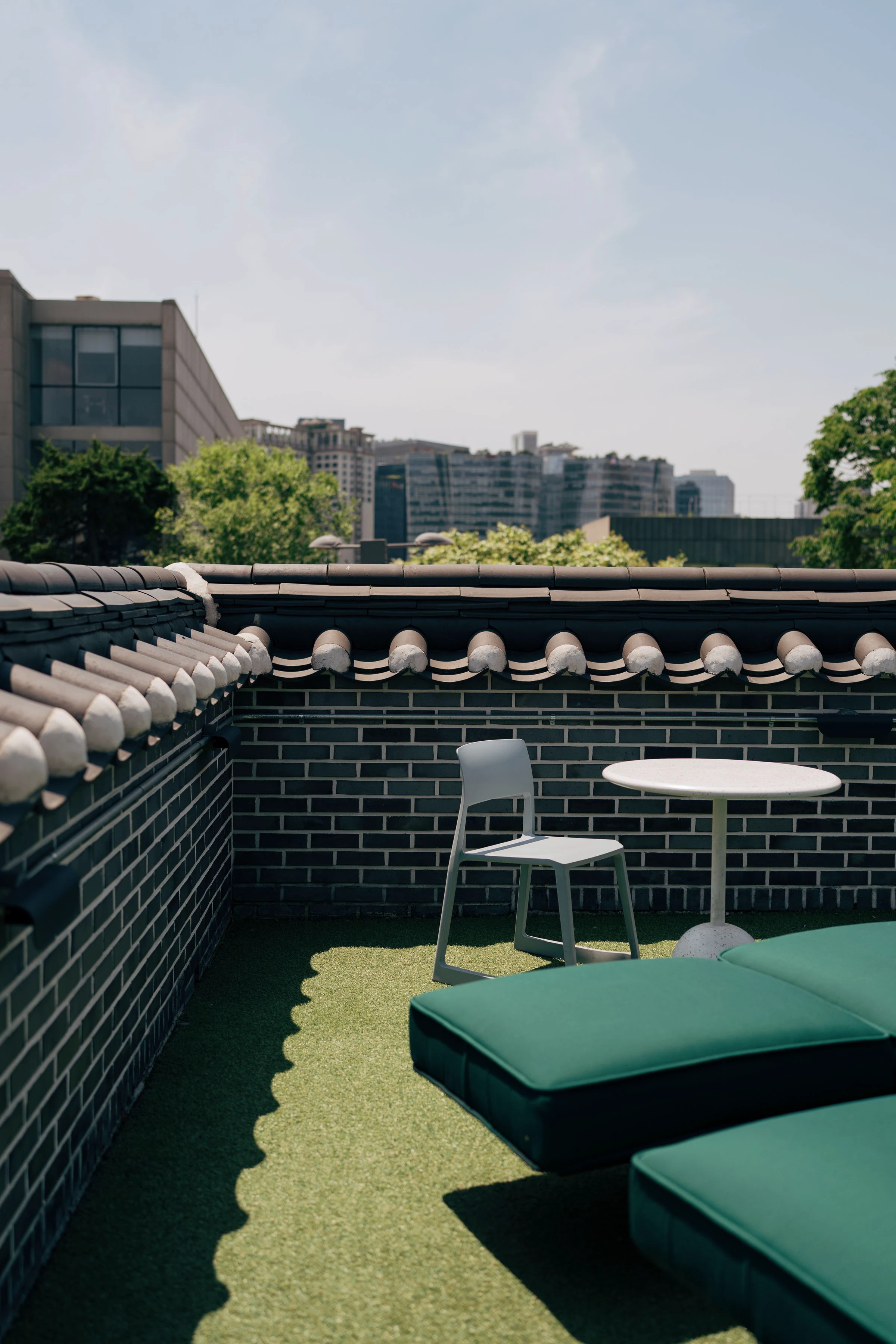 Sunny furnished rooftop terrace overlooking buildings in Seoul