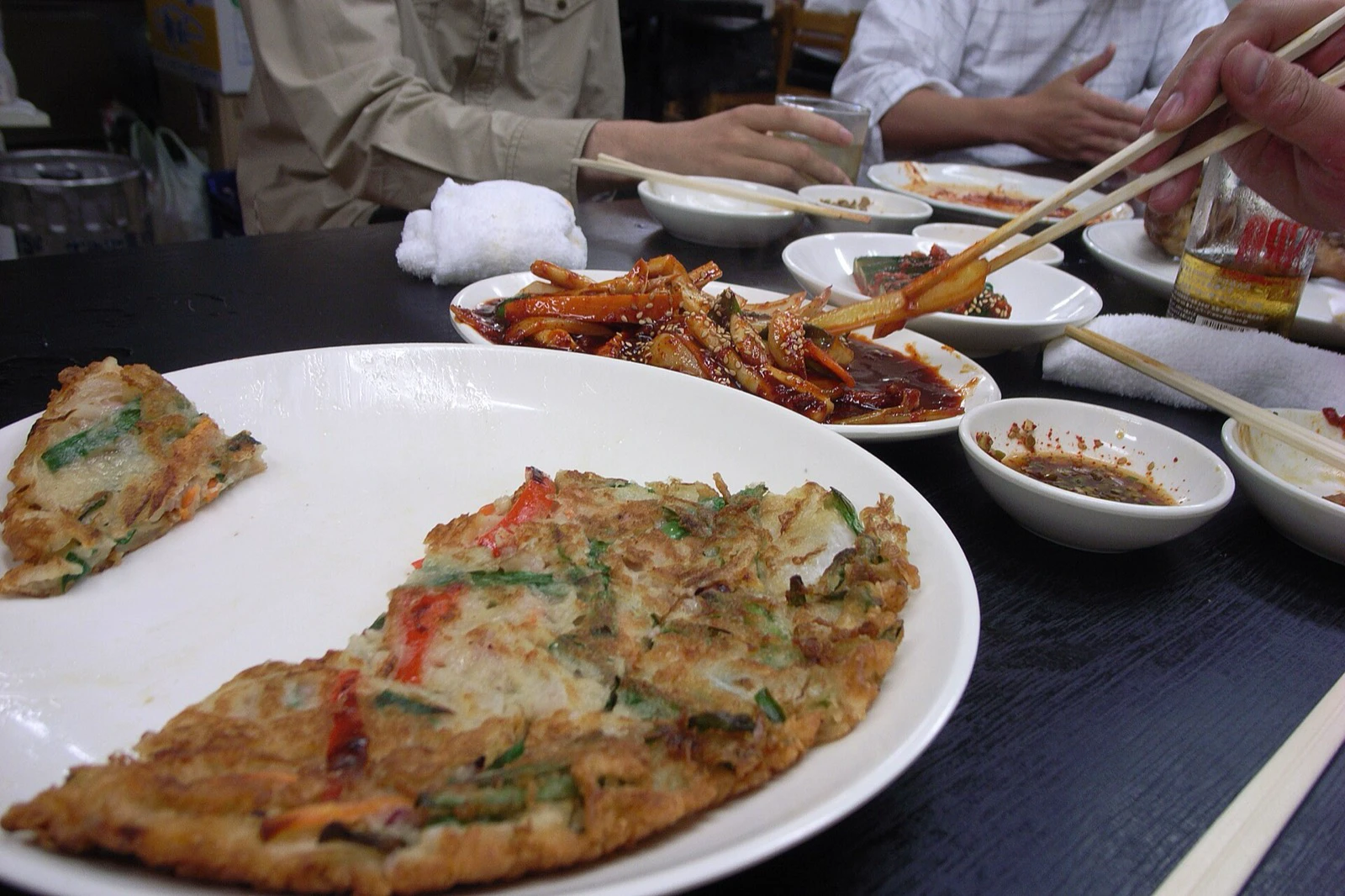 Pajeon disantap bersama di restoran Korea dengan hidangan pendamping di meja