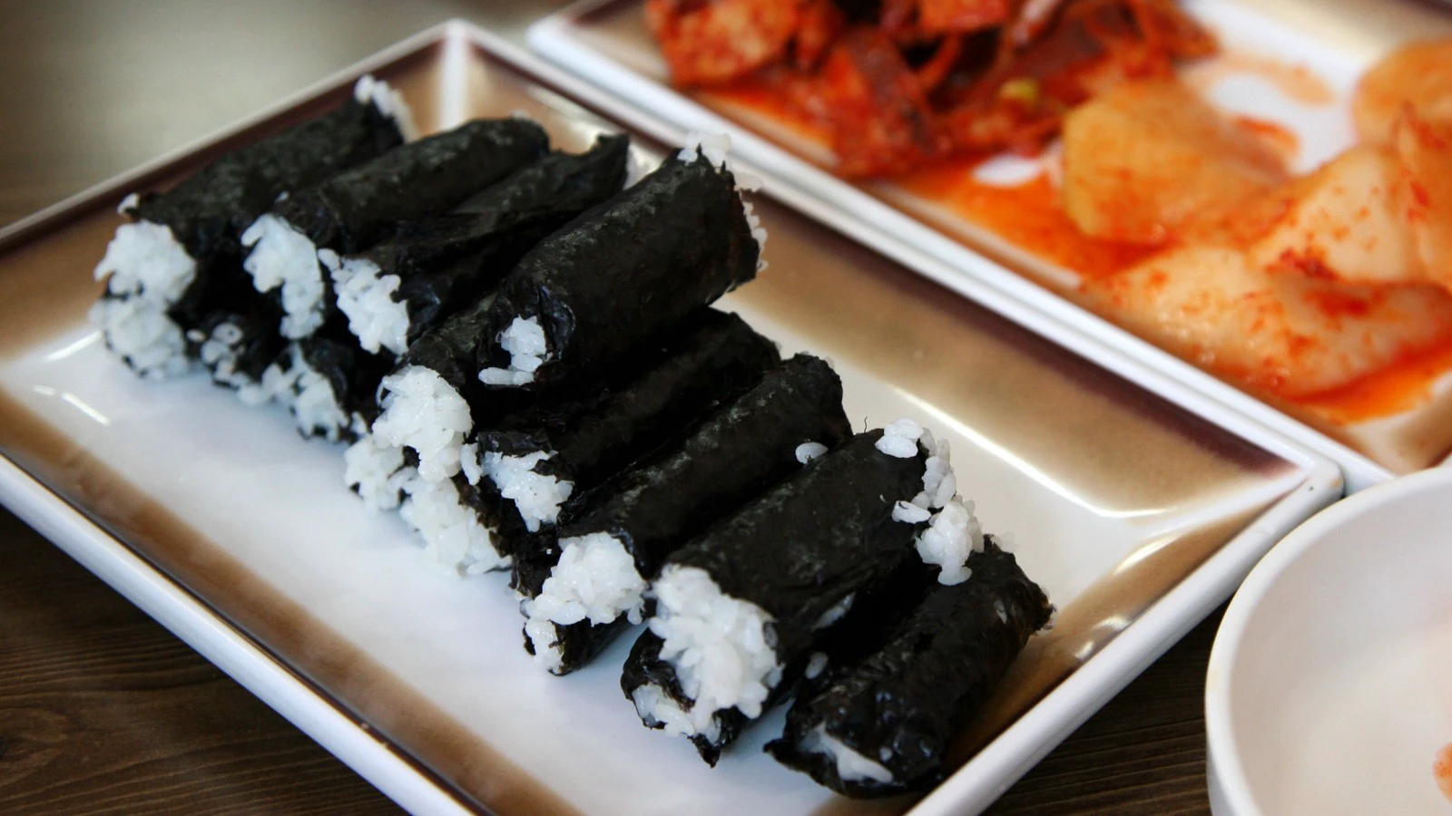 Gulungan Chungmu gimbap polos disajikan bersama kimchi lobak pedas dan cumi di Tongyeong