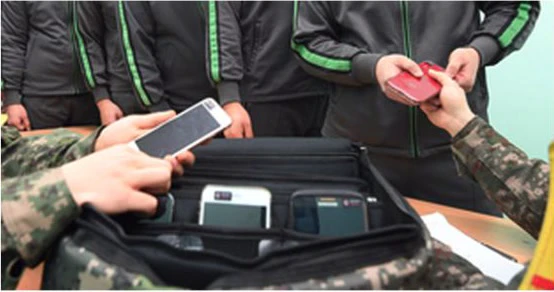 Soldiers’ hands hold smartphones above a padded phone-security case.
