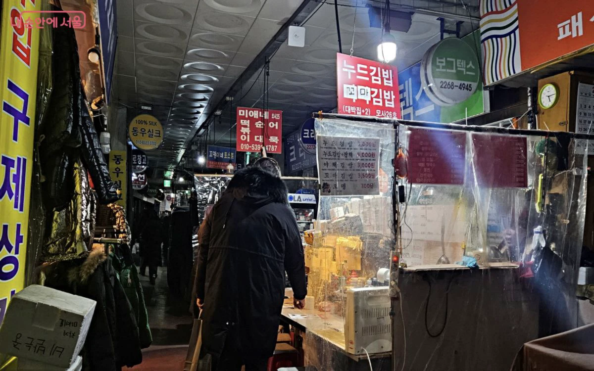 Food counters with posted menu prices inside Gwangjang Market