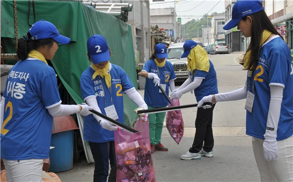 Campaign workers wearing blue uniforms collect litter at a market during a quiet campaign without songs or dancing in 2014