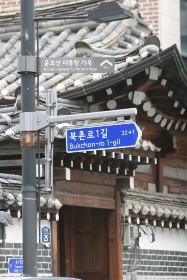Blue Bukchon-ro 1-gil road-name sign in front of a traditional Korean building