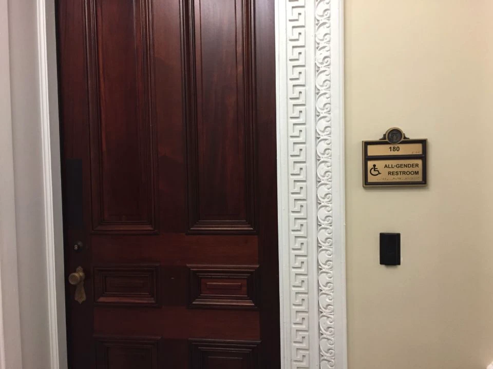 All-gender accessible restroom sign beside a solid wooden door