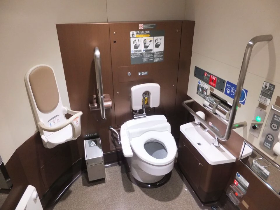 Wheelchair-accessible single-user toilet with grab bars and a child seat on an E6 Shinkansen
