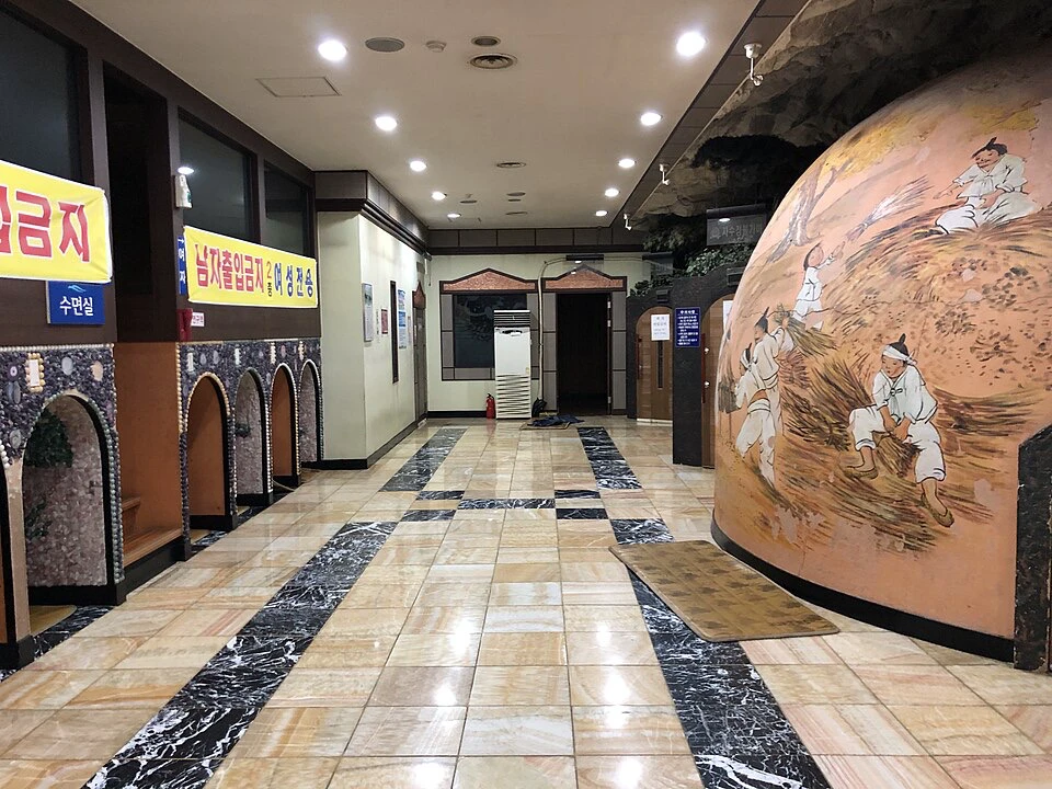 Koridor di dalam jjimjilbang Korea dengan pintu ruang tungku dan mural