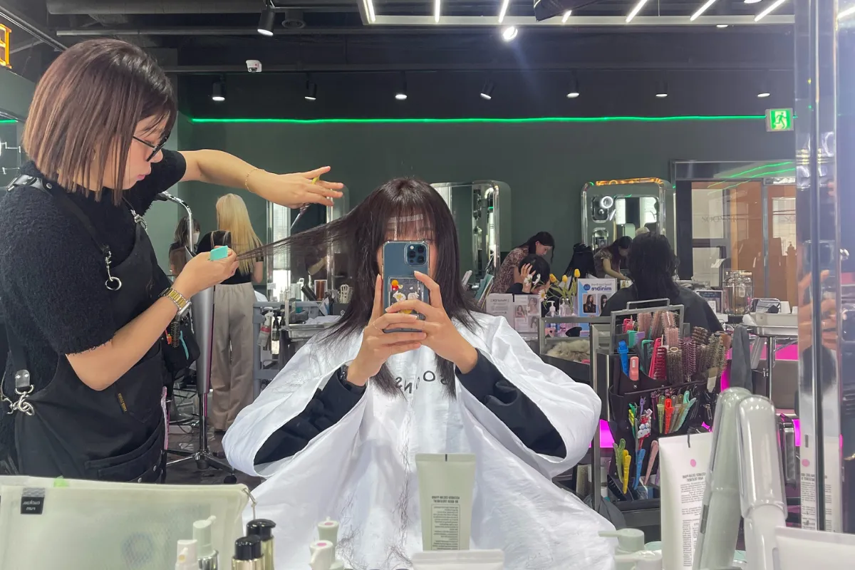 A stylist cutting hair at Soonsiki Hair in Seoul while the client checks the shape in a mirror